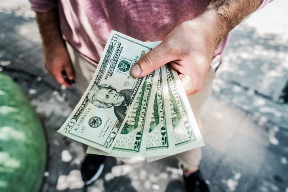 Mão segurando notas de dólar