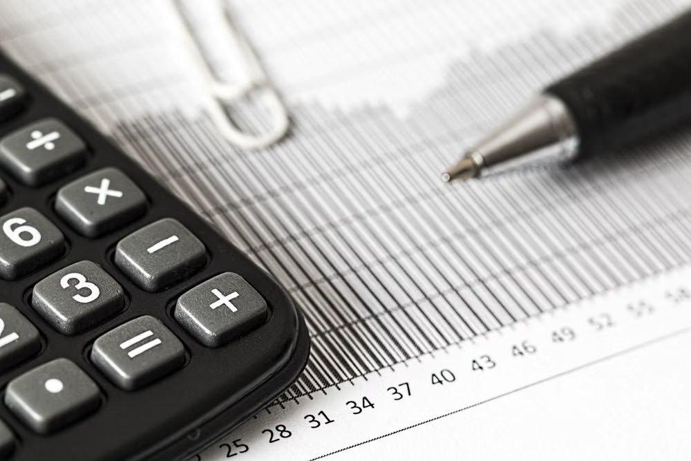 Calculadora e caneta sobre um gráfico financeiro
